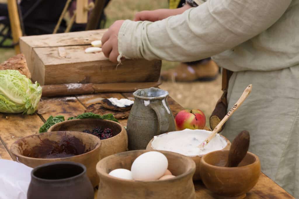 Medieval food preparation including eggs, berries, and cream in wooden bowls or trenchers at the Arkansas Renaissance Festival.