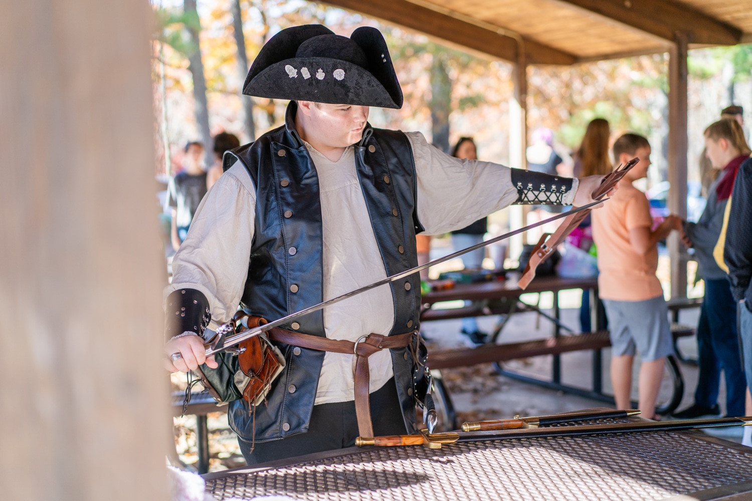 Teenage pirate cosplayer examines replica sword at the Arkansas Renaissance Festival.