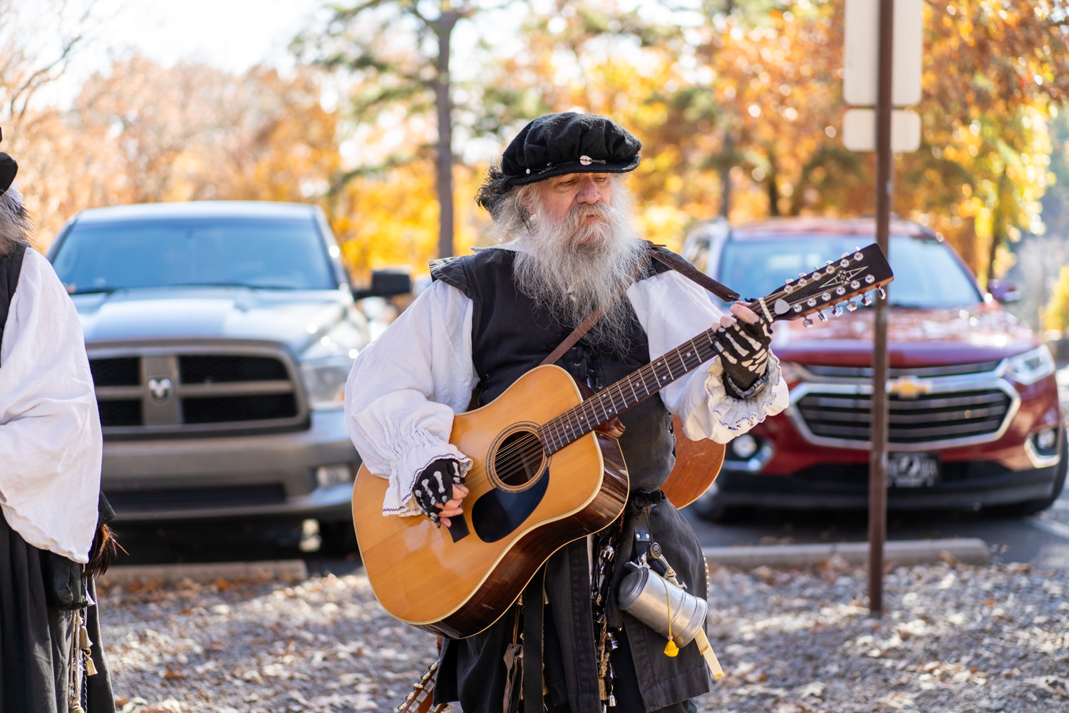 Older man with feather hat plays the guitar at the Arkansas Renaissance Festival.