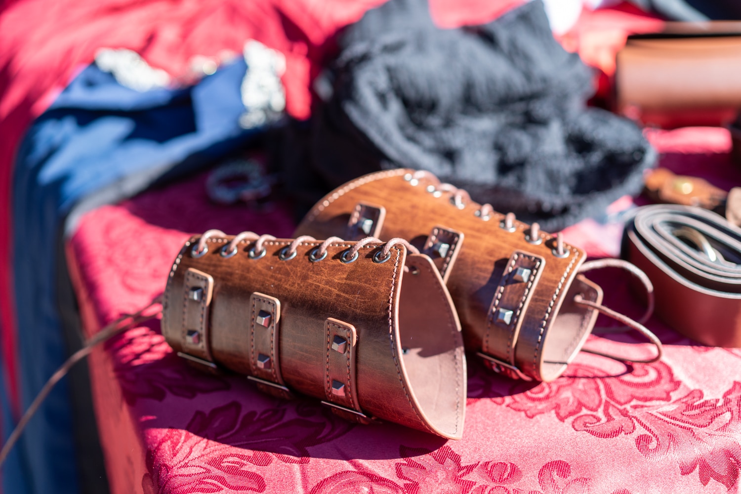 Two brown leather gauntlets lay on a red tablecloth at the Arkansas Renaissance Festival.