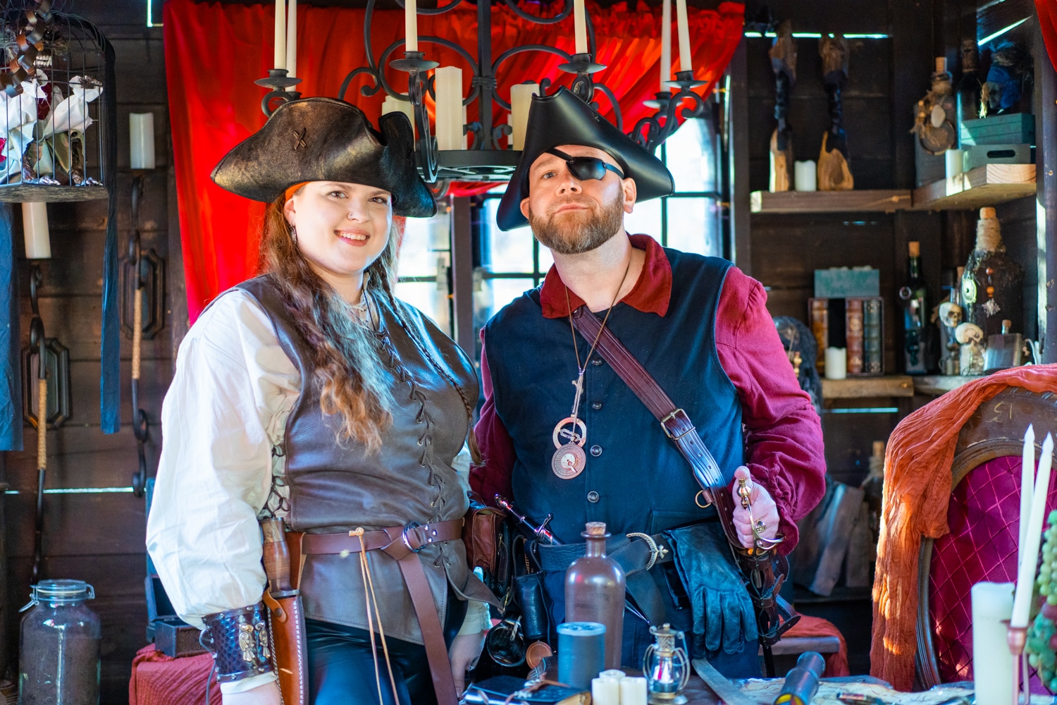 A man and woman dressed as pirates smile for the camera in a shop at the Arkansas Renaissance Festival.