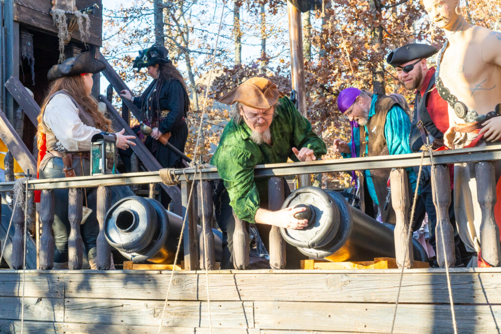 Men dressed as pirates prepare a cannon on a pirate ship at the Arkansas Renaissance Festival.