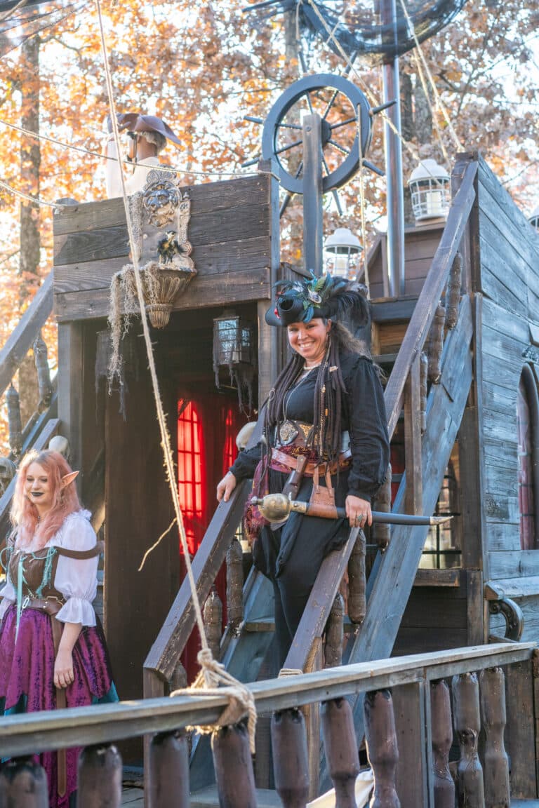 Woman cosplaying as pirate on a pirate ship smiling at the camera at the Arkansas Renaissance Festival.